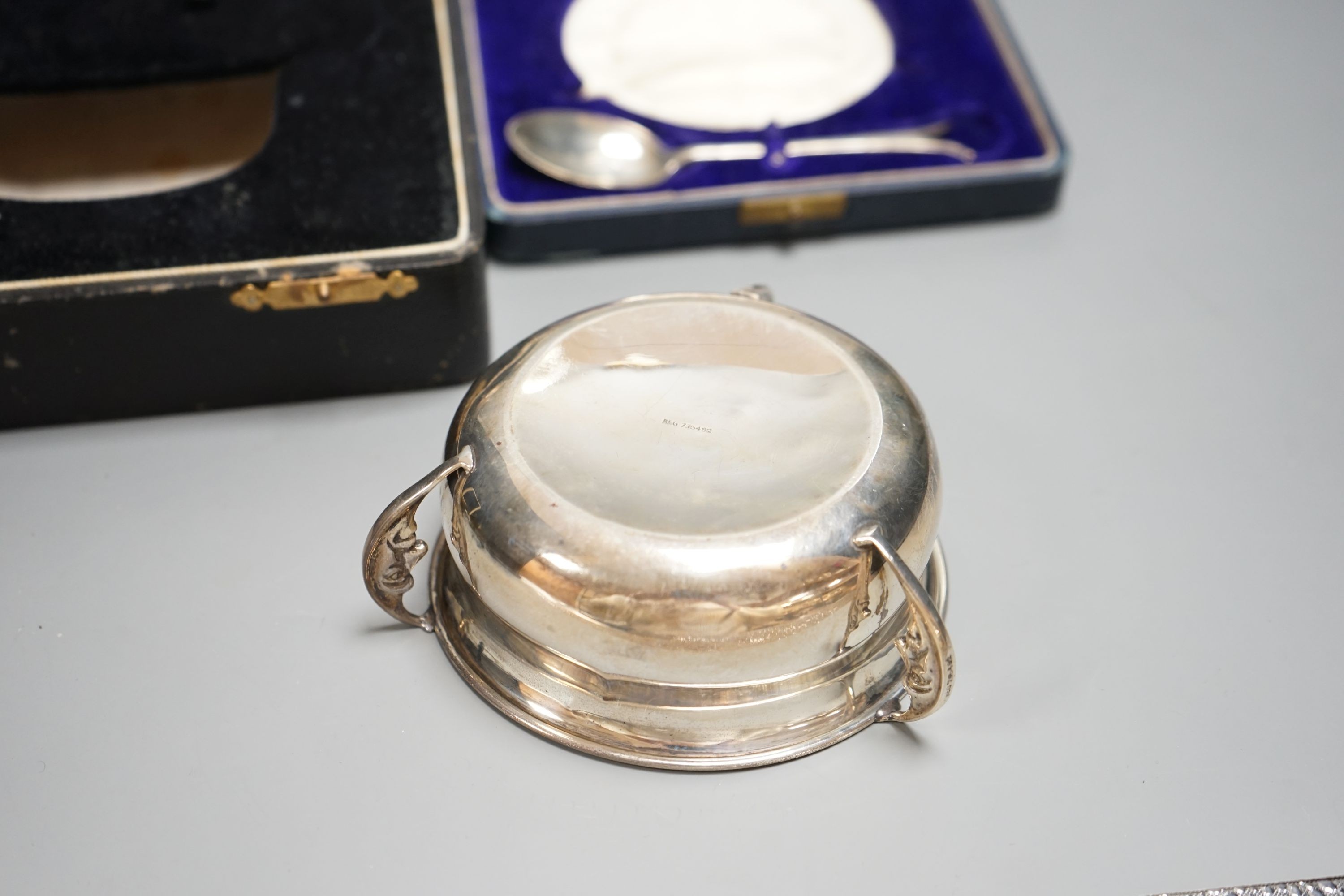 A cased George V silver three handle bowl and spoon, Birmingham, 1928 and a silver sauceboat, 7oz.